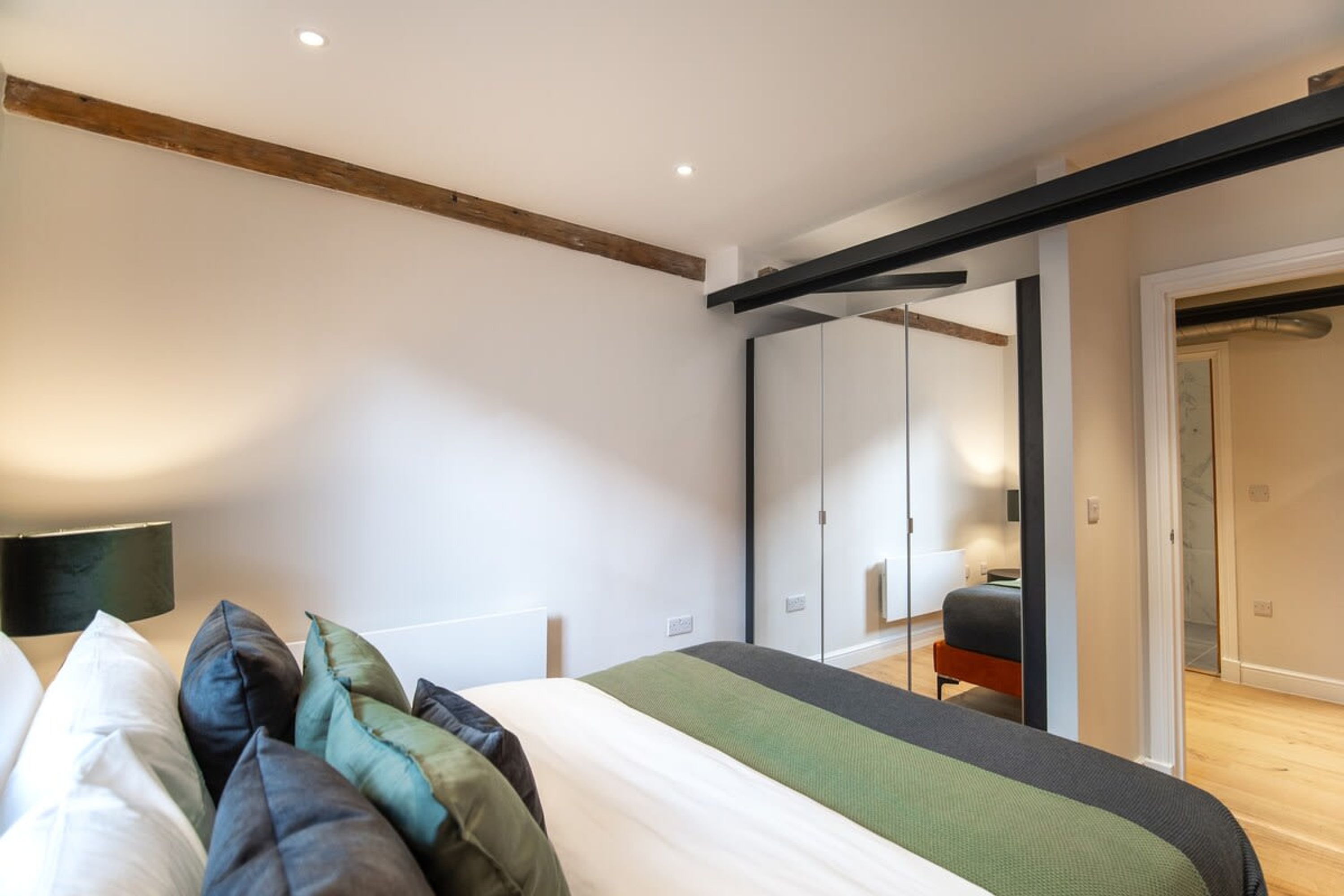 A modern bedroom with a bed, pillows, a bedside table, and a wardrobe.