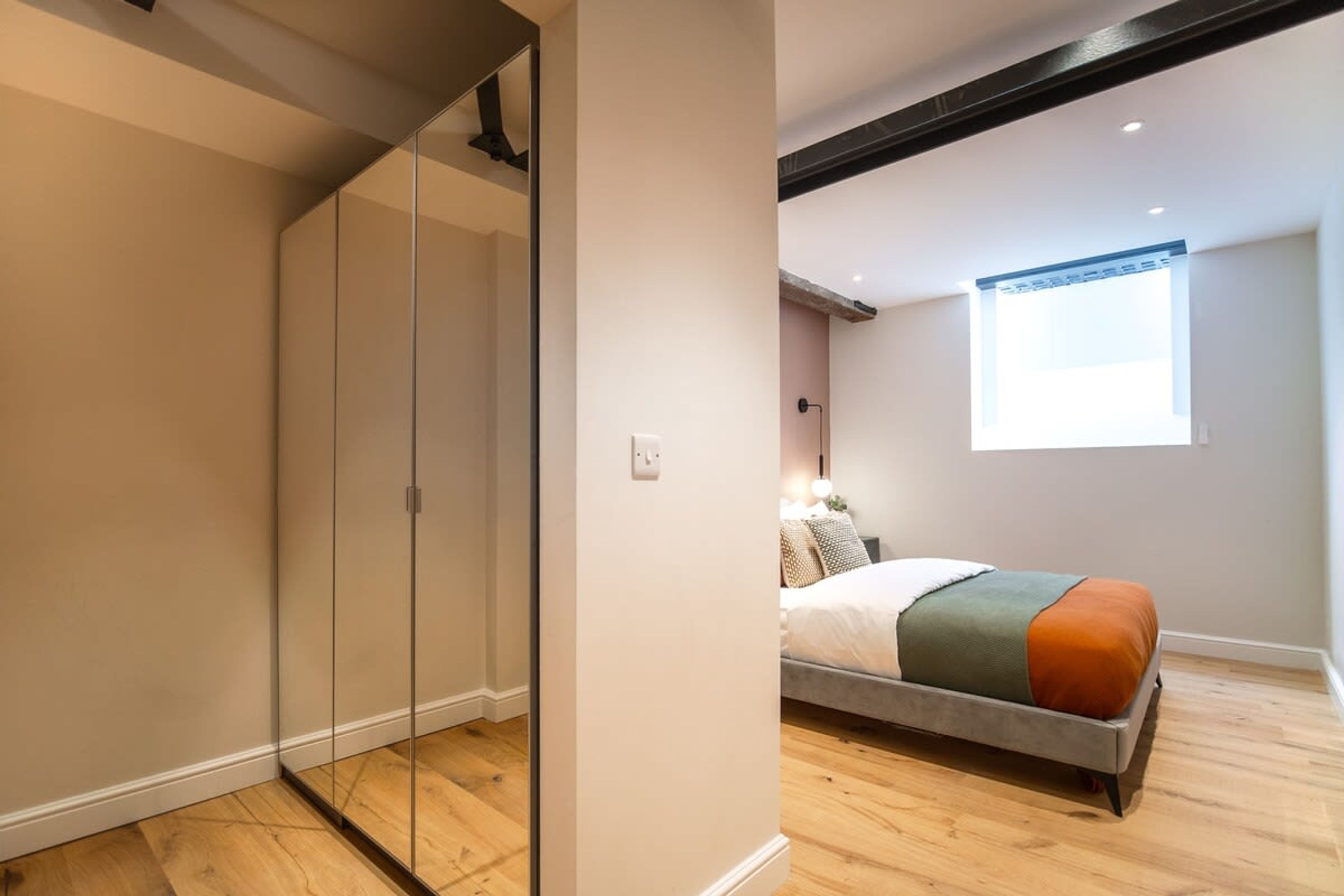 A bedroom with a bed, a wardrobe, and a window.