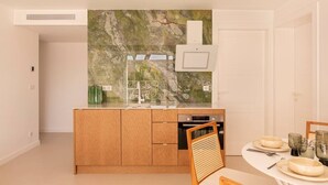 A modern kitchen with wooden cabinets, a built-in oven, and a glass backsplash. - Carla Rosa 7 Appartement Moderne Piscine - 2 BDR (Cannes)