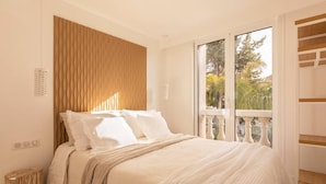 A bedroom with a bed, a window with a view of greenery, and a wooden headboard. - Carla Rosa 7 Appartement Moderne Piscine - 2 BDR (Cannes)