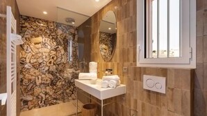 Une salle de bain avec un mur en pierre, un lavabo blanc et un miroir.