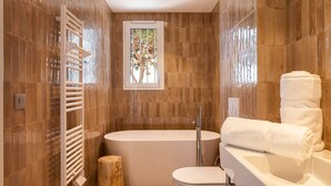 A modern bathroom with a freestanding bathtub, a toilet, and a towel rack.