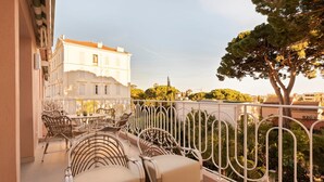 A balcony with wicker furniture and a view of a building with a red roof.