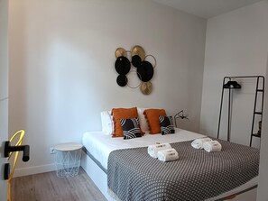A neatly arranged hotel room with a bed, a small round table, a floor lamp, and a wall-mounted hat rack. - 0A King Size Doublebed Near Gulbenkian by Ldapartments (Lisbon)