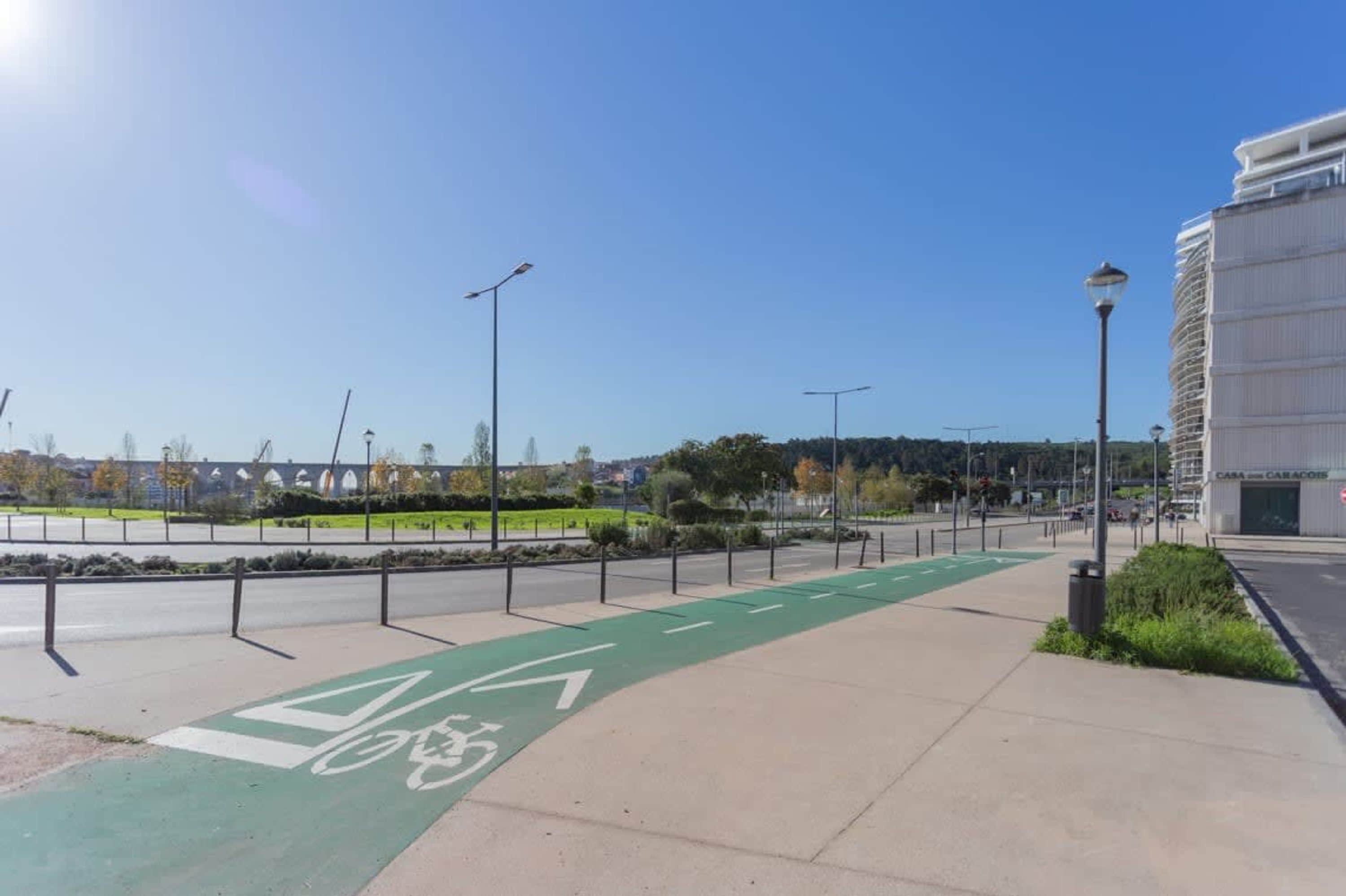 A bike lane with a green path and a white bicycle symbol, a sidewalk, and a building with "CASA" on it.