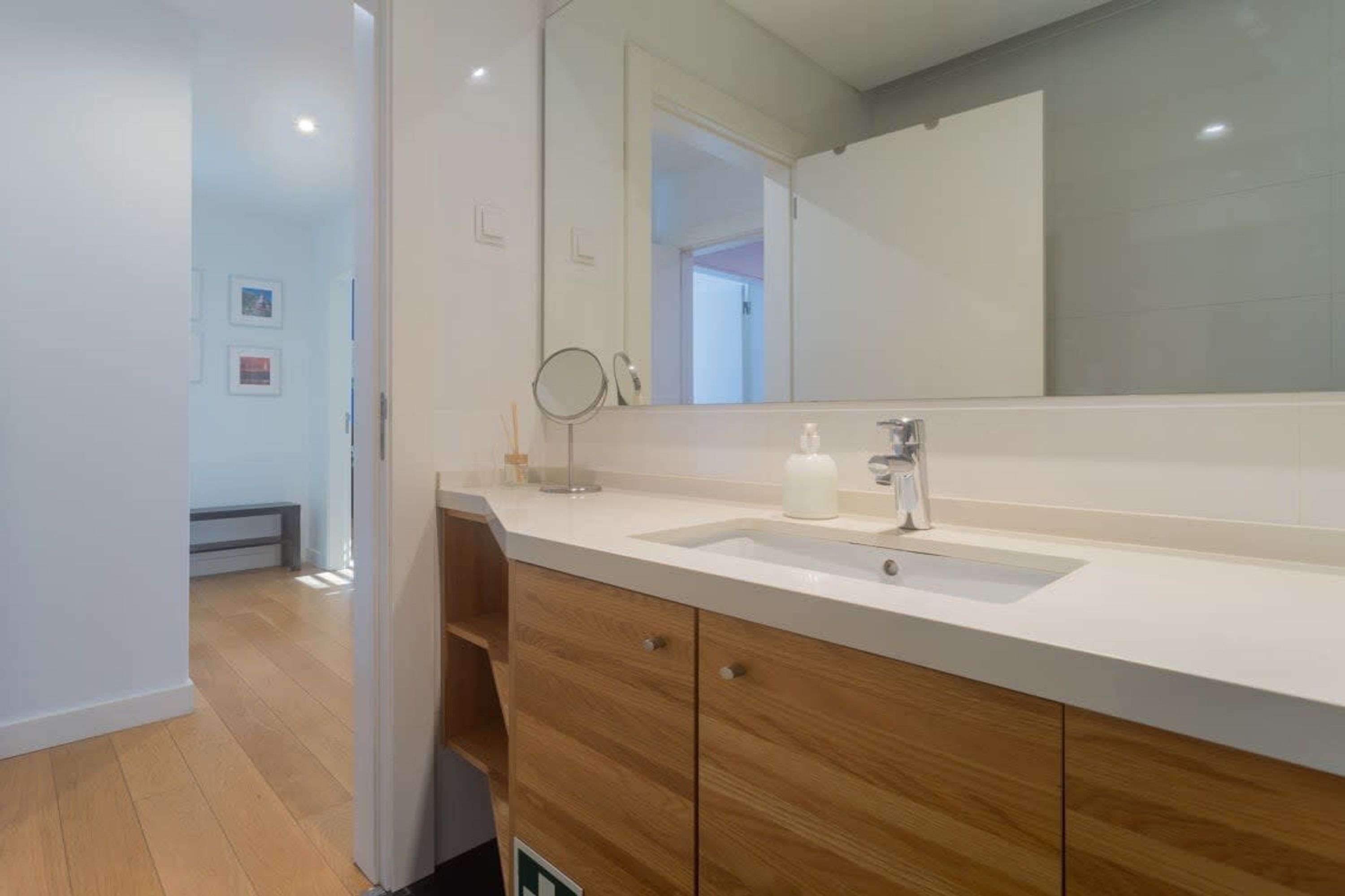 Un baño moderno con un espejo grande, un lavamanos y armarios de madera.