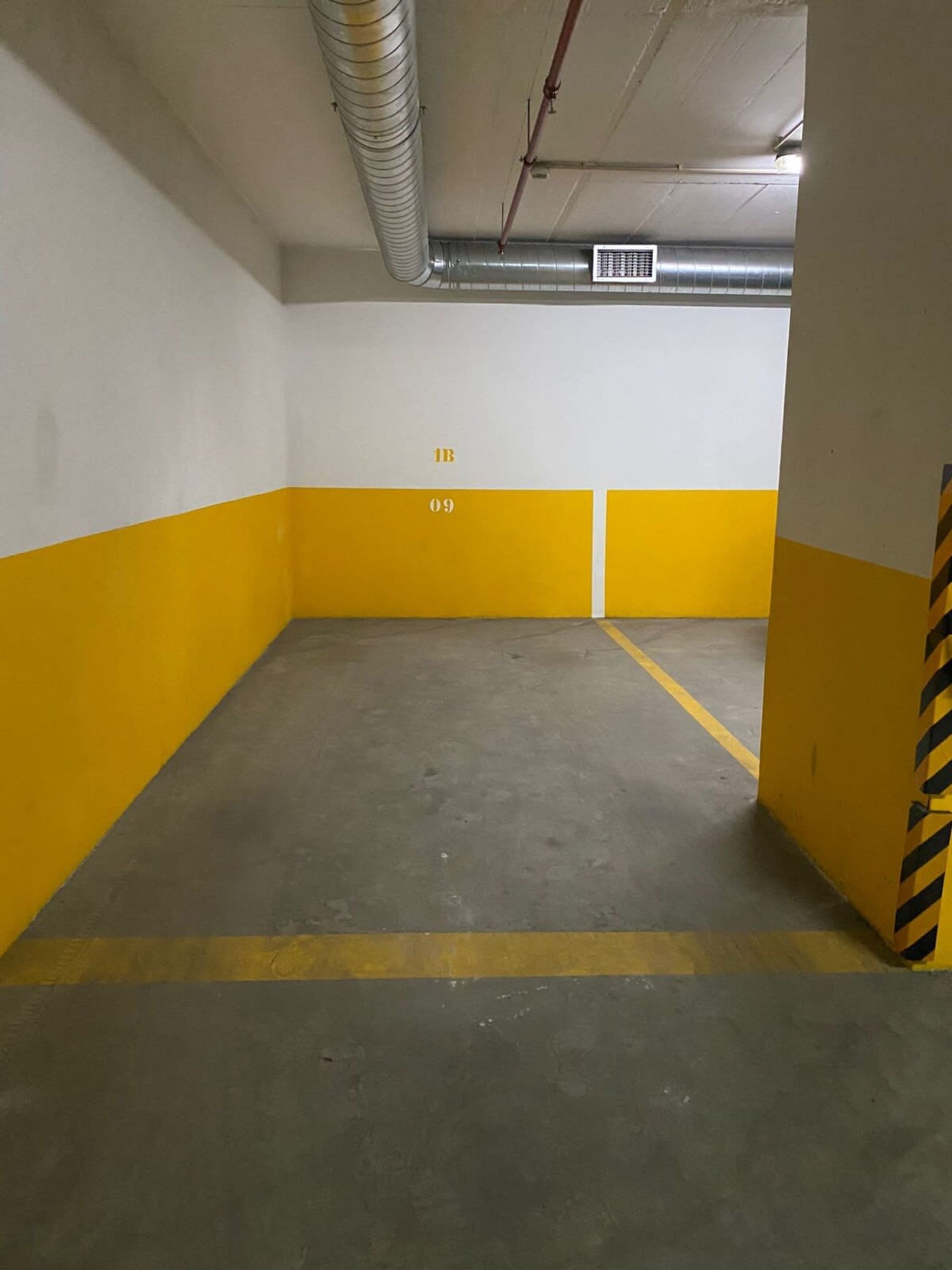 A parking garage with yellow and white walls, numbered parking spots, and a concrete floor.