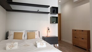 A modern bedroom with a bed, bedside tables, a nightstand, a wooden wardrobe, and built-in shelves. - 1C Spacious Studio Near Gulbenkian by Ldapartments (Lisbon)