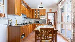 Una cocina con armarios de madera, una mesa de comedor con sillas y vistas a través de un ventanal.