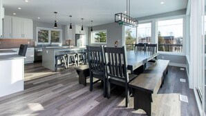 A modern kitchen with a large island, dark wooden chairs, and pendant lighting. - High-tech Mountain Luxury Fitness Hot Tub BBQ (The Blue Mountains)