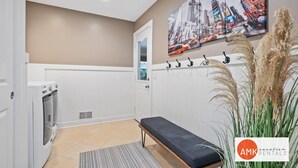 A clean, modern bathroom with a bench, a wall-mounted towel rack, and a large cityscape painting. - Destined for Relaxation (Saugatuck)