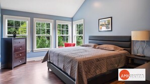 A bedroom with a bed, a dresser, a chair, and a nightstand with a lamp. - Destined for Relaxation (Saugatuck)