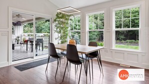 A dining area with a wooden table, black chairs, and a hanging plant. - Destined for Relaxation (Saugatuck)