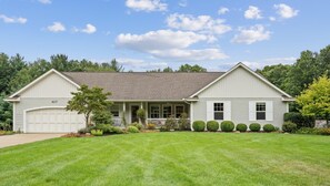 A two-story house with a garage, a covered porch, and a well-maintained lawn. - Destined for Relaxation (Saugatuck)