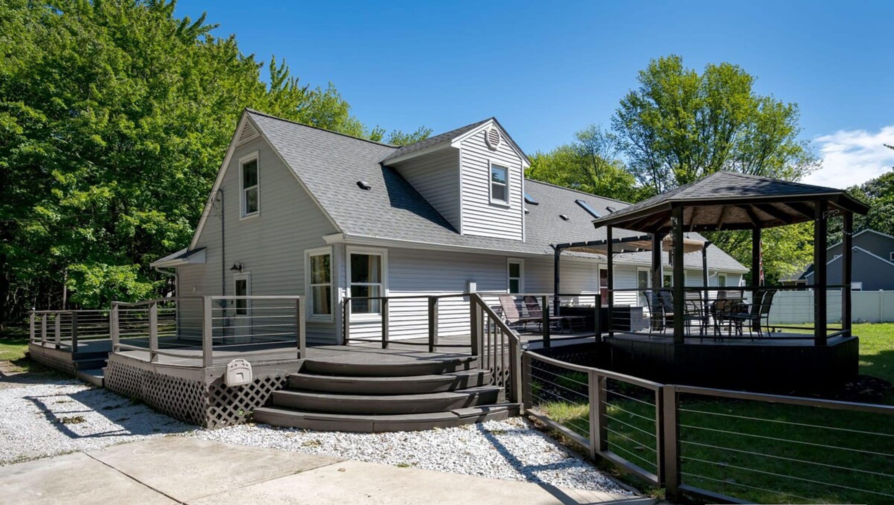 A two-story house with a covered porch and a small gazebo.