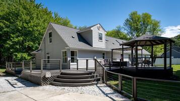 A two-story house with a covered porch and a small gazebo.