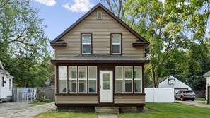 A two-story house with a front porch, a garage, and a basketball hoop in the backyard.
