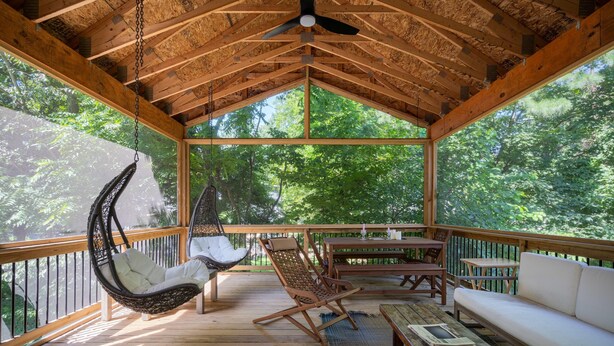 A wooden deck with a hanging chair, a cushioned chair, and a sofa. - Beautiful Custom Lake House (Holland)