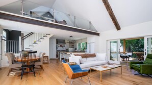 A spacious living area with a staircase leading to an upper level, a dining area with a round table and chairs, and a seating area with a sofa and armchairs. - Beautiful Custom Lake House (Holland)