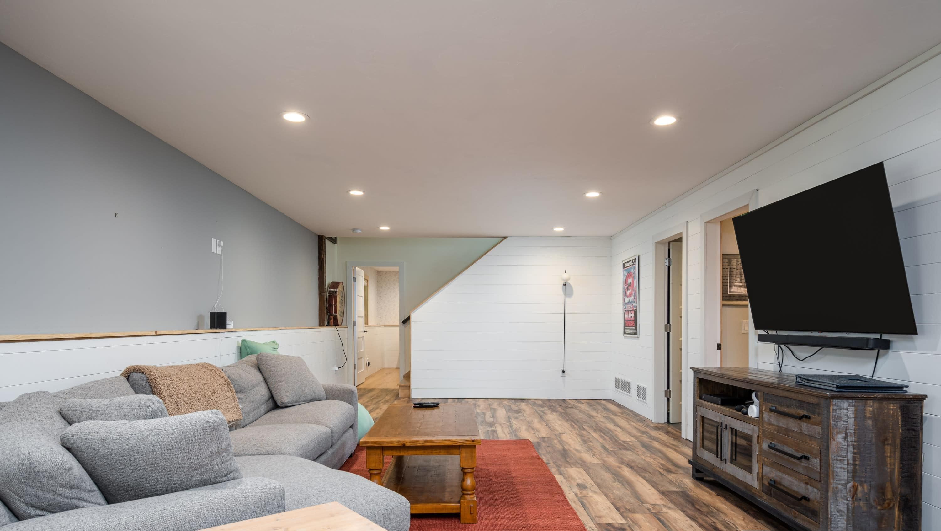 Una sala de estar moderna con un sofá seccional gris, una mesa de centro de madera y un televisor sobre un mueble de madera.