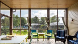 A covered outdoor area with a table and chairs, large windows, and a view of greenery and buildings. - Lake Life Getaway - Condo Near Downtown (Douglas)