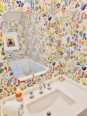 A bathroom with a white sink, a mirror above it, and a colorful floral wallpaper. - Charming Bayview - Downtown Condo With Pool (Saugatuck)