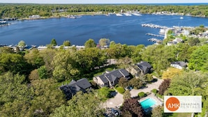 An aerial view of a lakeside community with residential buildings, docks, and boats. - Charming Bayview - Downtown Condo With Pool (Saugatuck)
