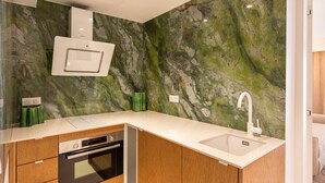 Una cucina moderna con forno a incasso, lavello e pannello di marmo.