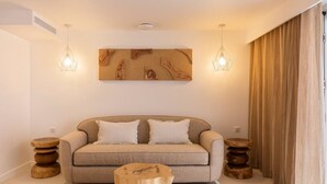 Un soggiorno moderno con un divano color beige, due tavolini di legno, un tavolino da caffè in legno e due lampade a sospensione.