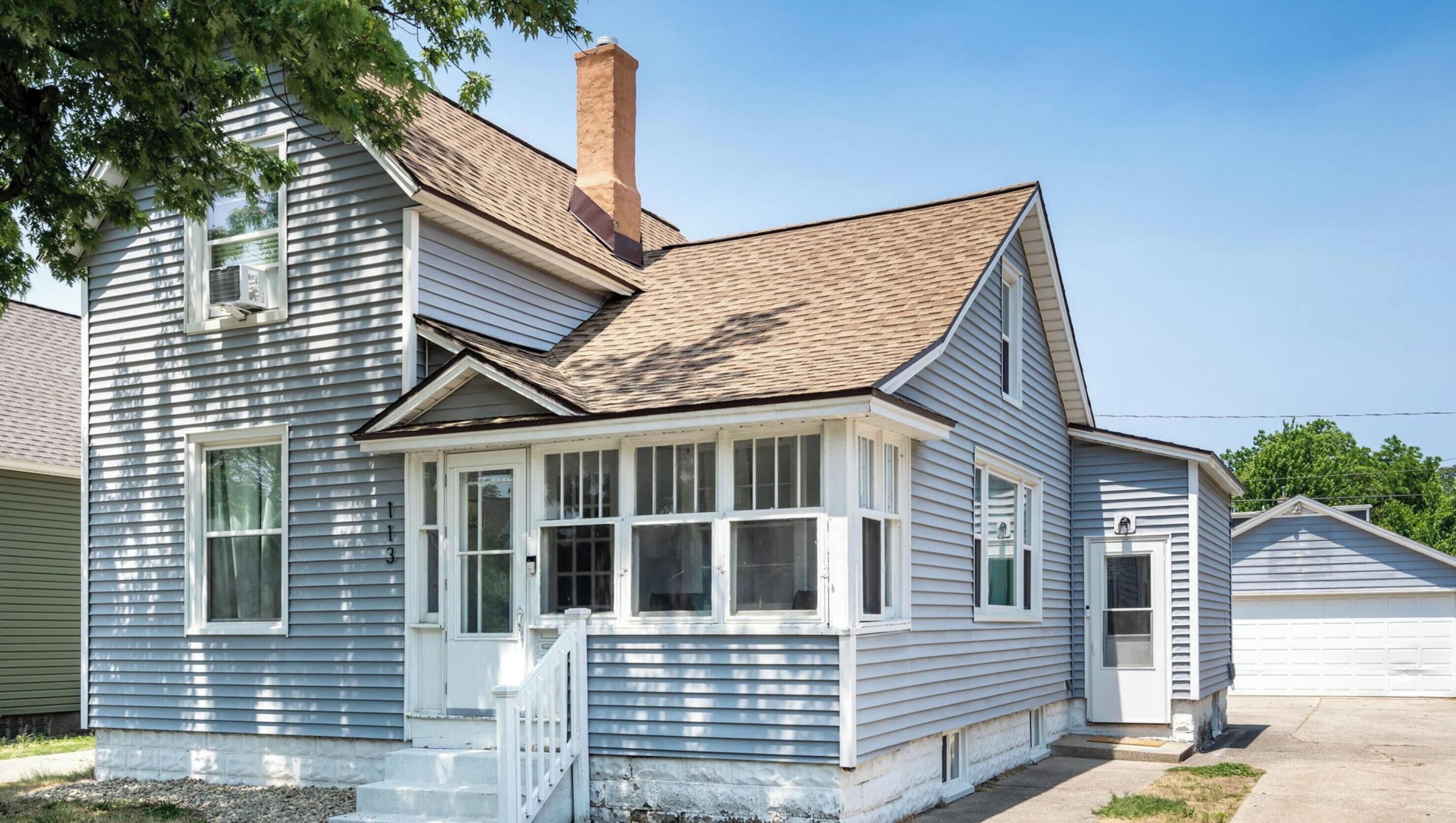 A two-story house with a front porch, a chimney, and a garage.