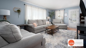 A modern living room with a grey sofa set, a wooden coffee table, and a large window with white curtains. - Holland Hideaway in Holland (Holland)