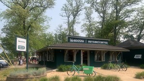 Un edificio verde con un letrero que dice "WOOSAH OUTSIDE COFFEE".