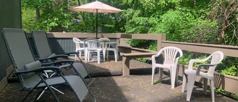 Un patio al aire libre con asientos y una mesa, rodeado de follaje.