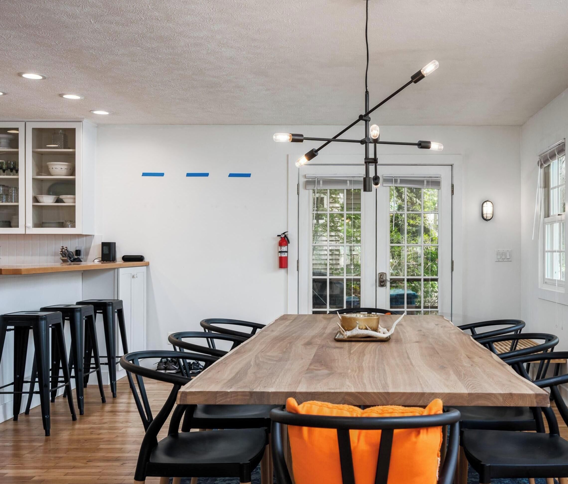 A modern dining area with a wooden table, black chairs, and a pendant light.