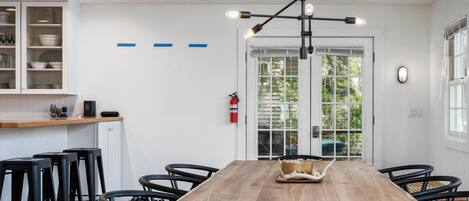 A modern dining area with a wooden table, black chairs, and a pendant light.