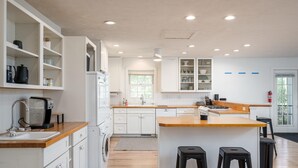 Une cuisine moderne avec des meubles blancs, des plans de travail en bois et un îlot central doté de tabourets.