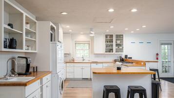Una cocina moderna con armarios blancos, encimeras de madera y una isla central con taburetes.