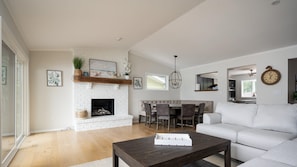 Una sala de estar moderna con chimenea, un comedor y una cocina al fondo.