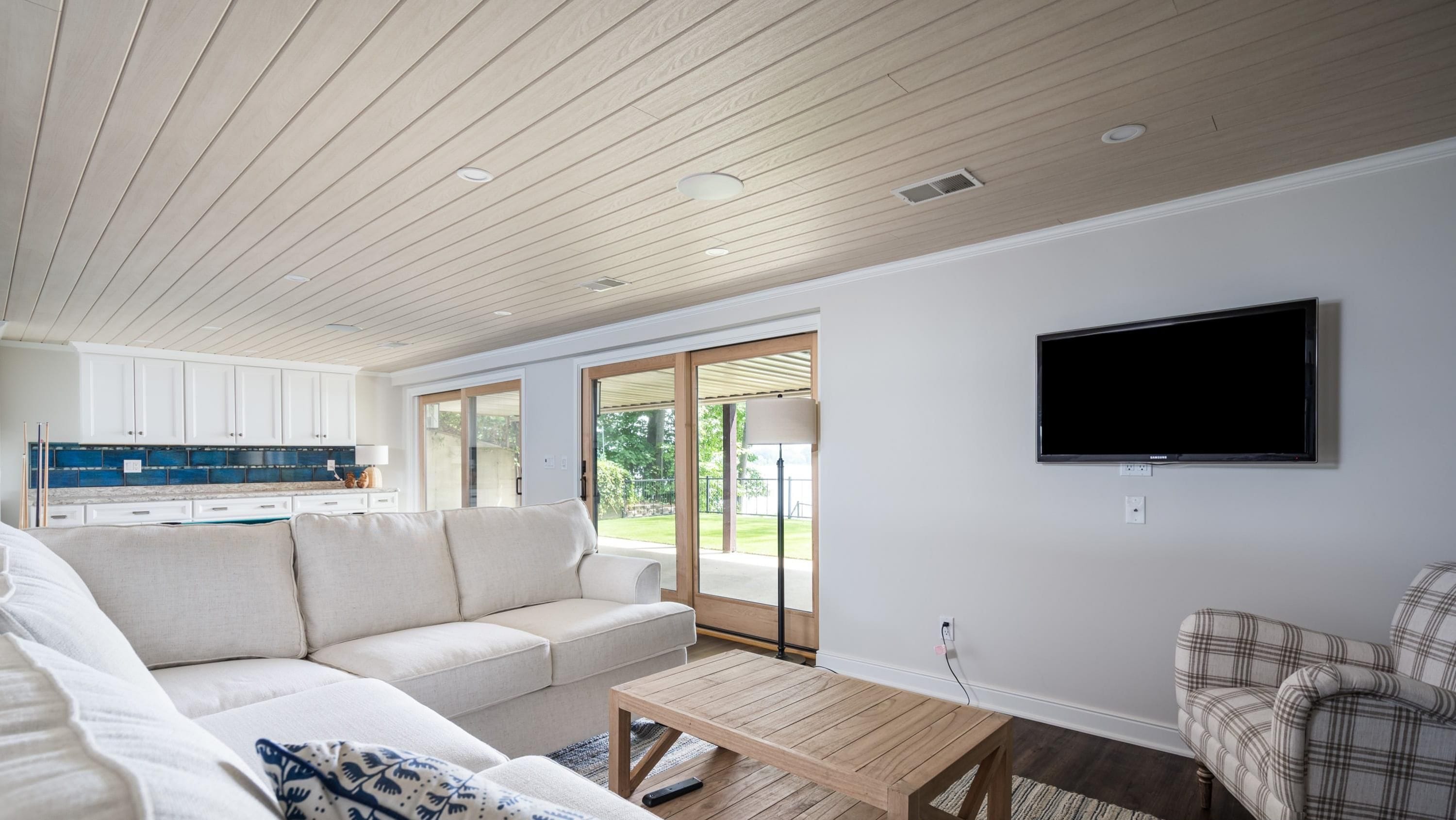 Un salon moderne avec un canapé, une table basse et un téléviseur à écran plat fixé au mur.