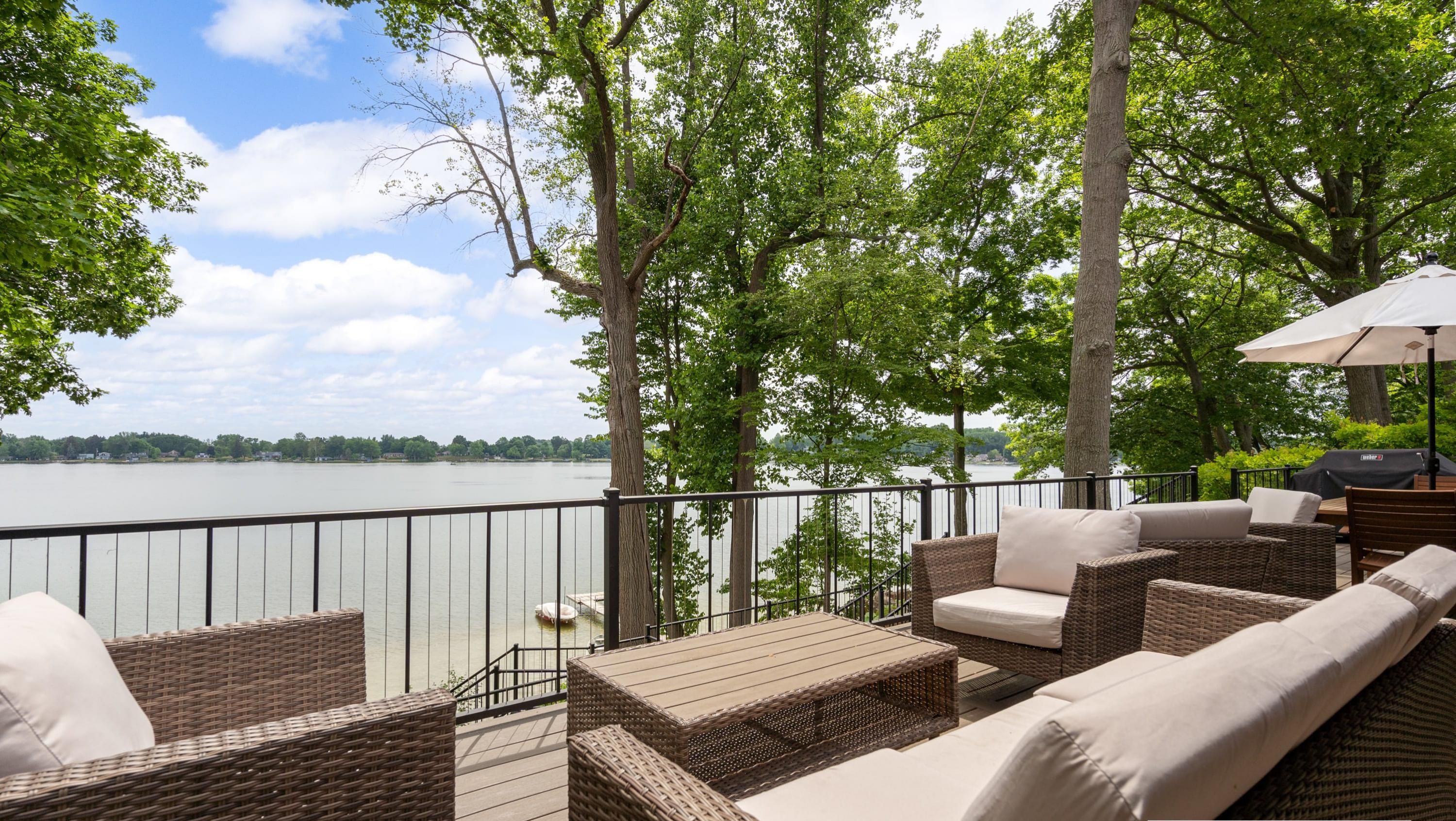 A deck with wicker furniture and a view of a lake.