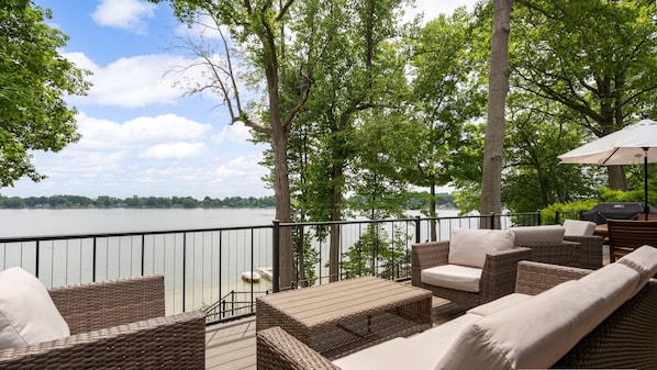 Terraza con mobiliario de mimbre y vista a un lago.