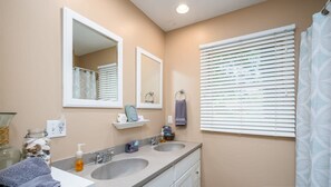 A bathroom with two sinks, a mirror, a towel rack, and a window with blinds. - Lakeside Retreat - Waterfront Quiet Neighborhood (Muskegon)