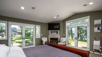 A bedroom with a large bed, a fireplace, and sliding glass doors leading to a backyard.