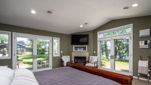 Un dormitorio con una cama grande, una chimenea y puertas corredizas de vidrio que dan a un patio trasero.