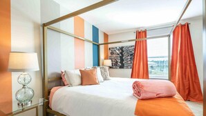 Habitación de hotel moderna con una cama con dosel, una mesita de vidrio y vistas de la ciudad a través de amplias ventanas.
