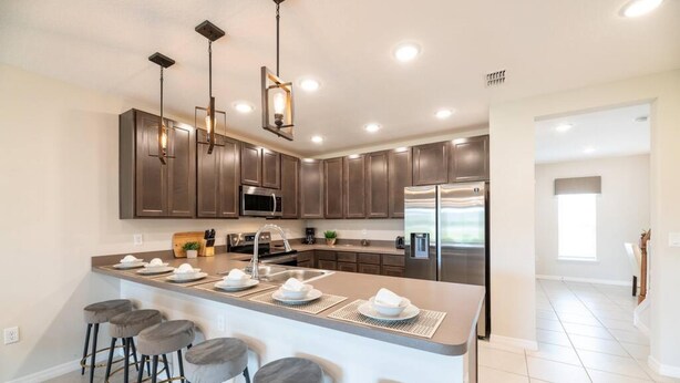 Una cocina moderna con armarios de madera oscura, electrodomésticos de acero inoxidable y una isla central con taburetes de bar.