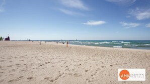 Ein Strand mit einem Rettungsturm, ruhiger See und blauem Himmel.