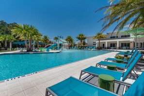 A swimming pool with lounge chairs and palm trees.