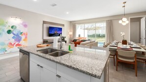 A modern kitchen with granite countertops, a dishwasher, and a dining area with a table and chairs. - Super Close- Disney s Parks w Theme Rooms Pool (Lake Buena Vista)