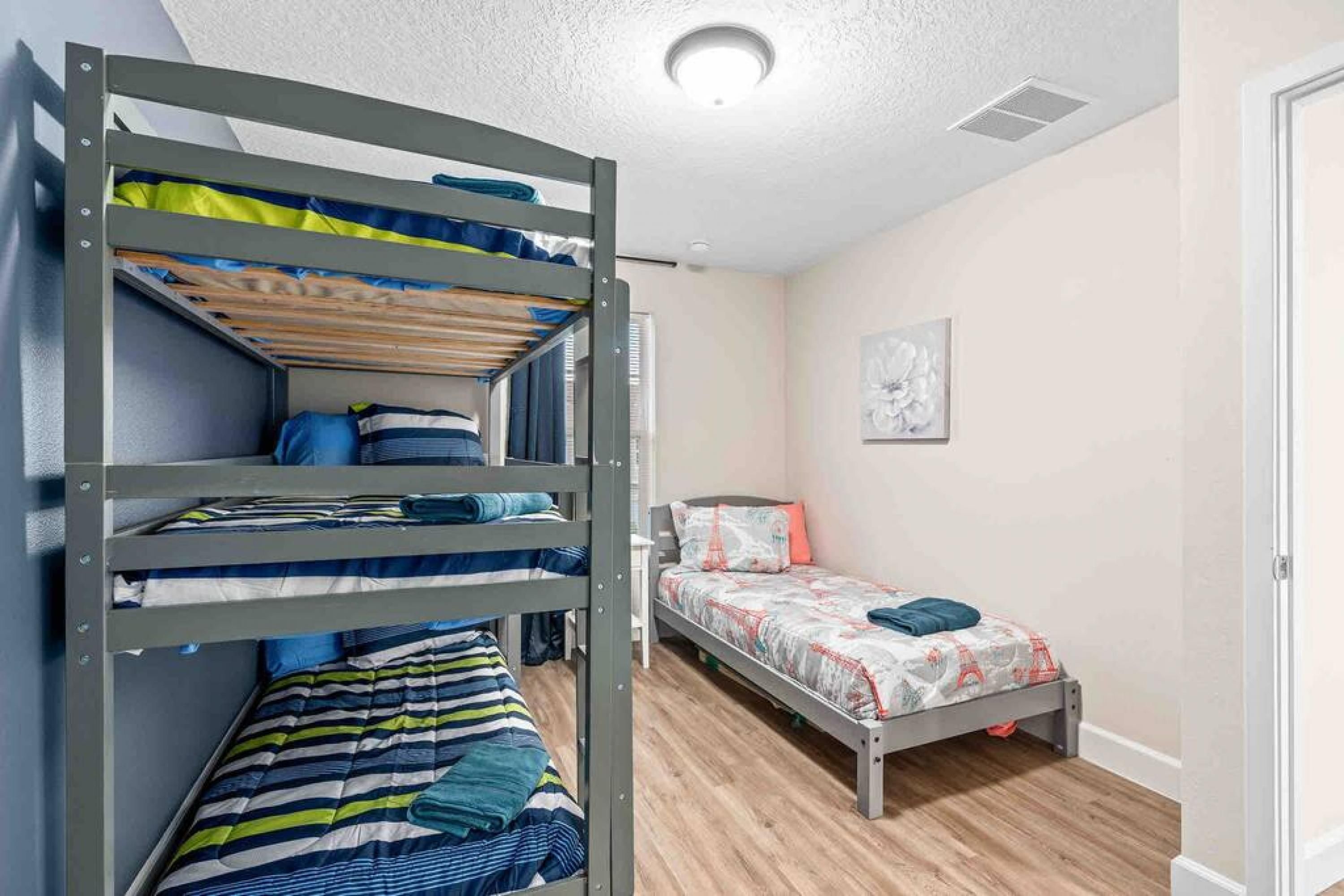 Une chambre avec un lit superposé, un lit simple et un petit bureau.